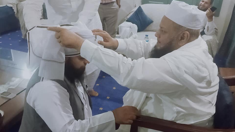 Religious scholar tying turban at ceremony